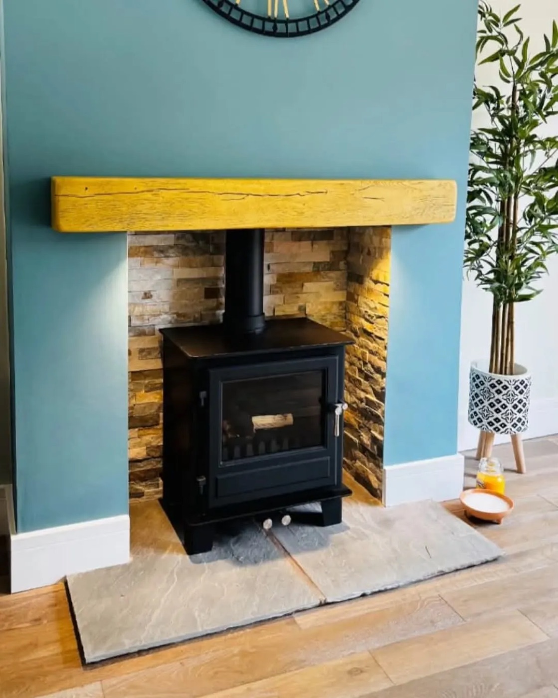 Black multi-fuel stove with a solid oak beam and slate chamber in a blue living room