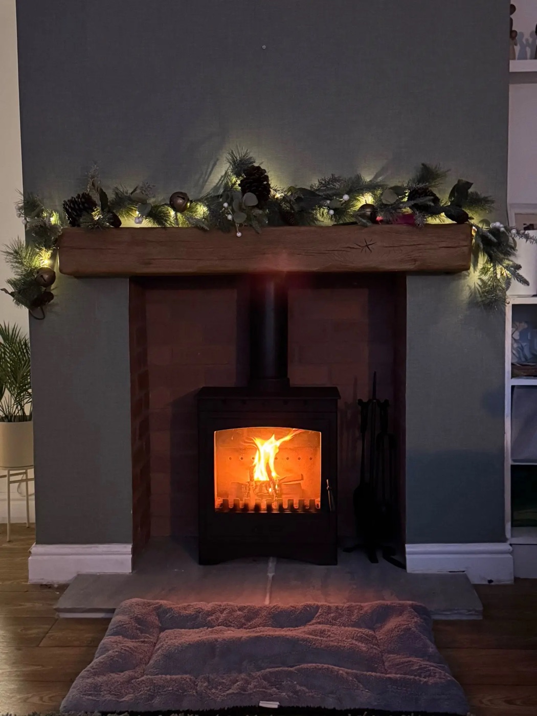 Lit stove with an oak beam dressed for Christmas